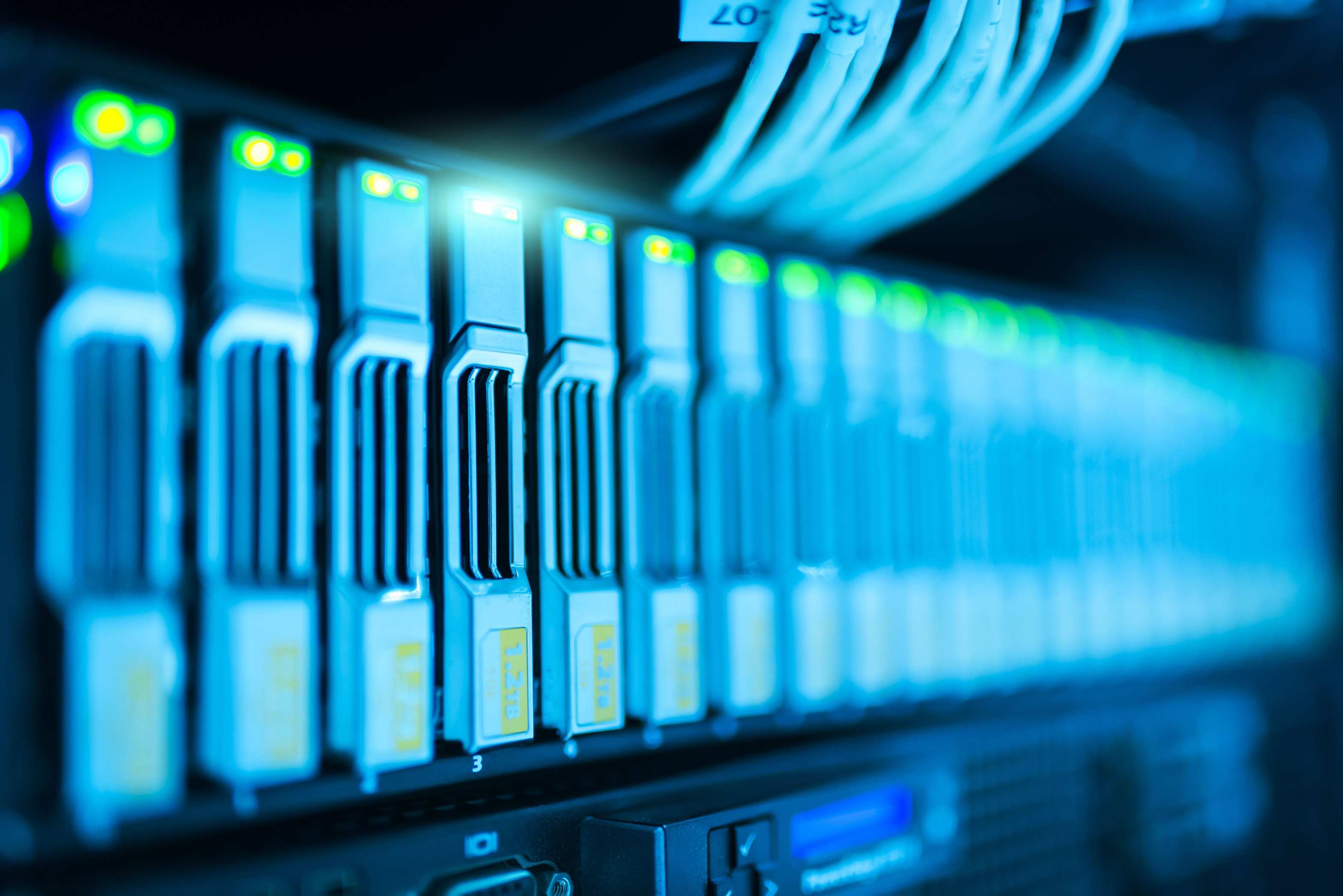 Server racks in a data facility with glowing lights in a modern data center